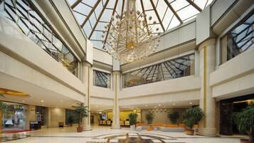 A spacious atrium with a high ceiling, large windows, and a central chandelier.