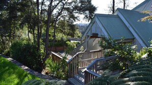 A wooden staircase leading to a building with a green roof, surrounded by lush greenery and trees. - Atea Lodge (Coromandel)