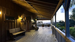 A covered outdoor seating area with wooden benches and tables, overlooking a scenic landscape. - Atea Lodge (Coromandel)