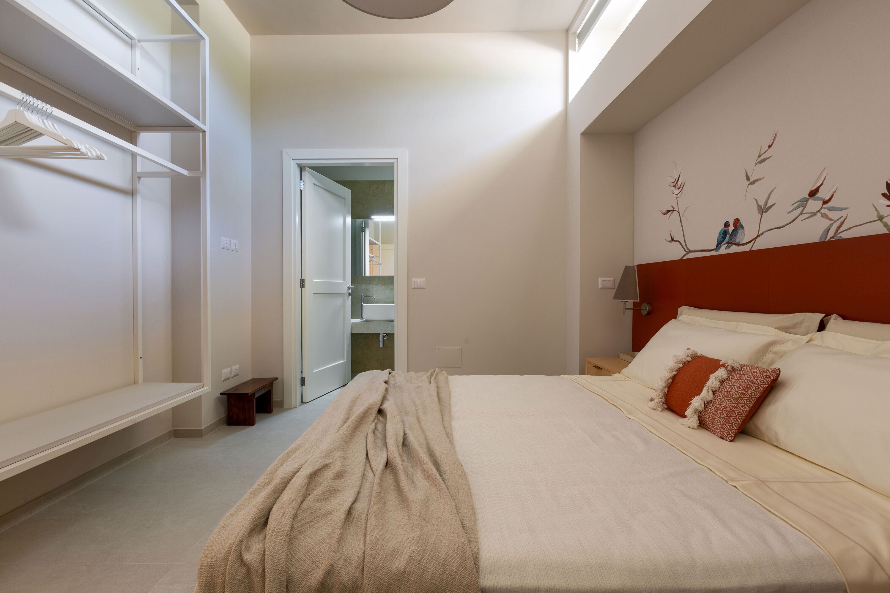 A bedroom with a bed, a wardrobe, and a bathroom visible through an open door.