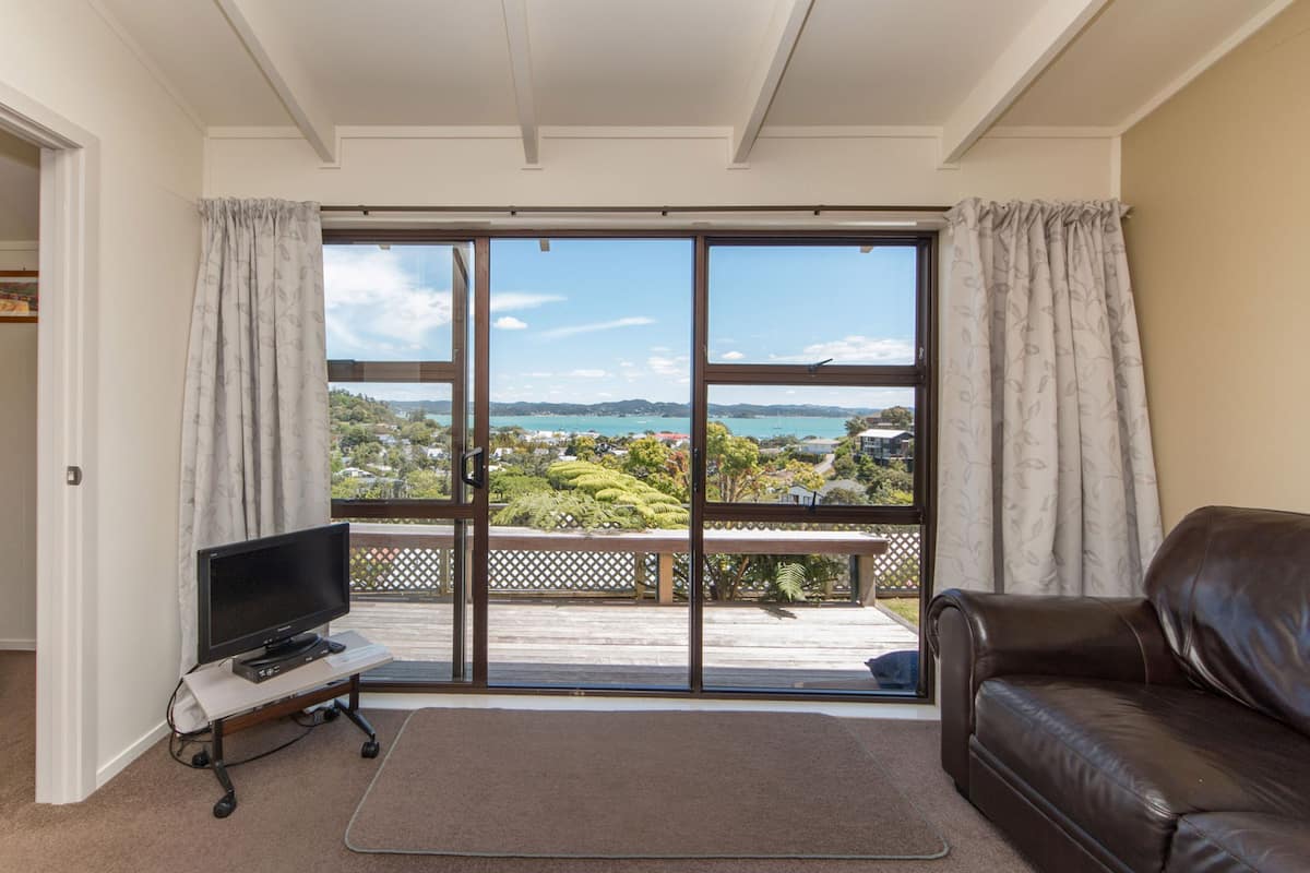 A room with a sliding glass door leading to a balcony with a view of a coastal landscape.