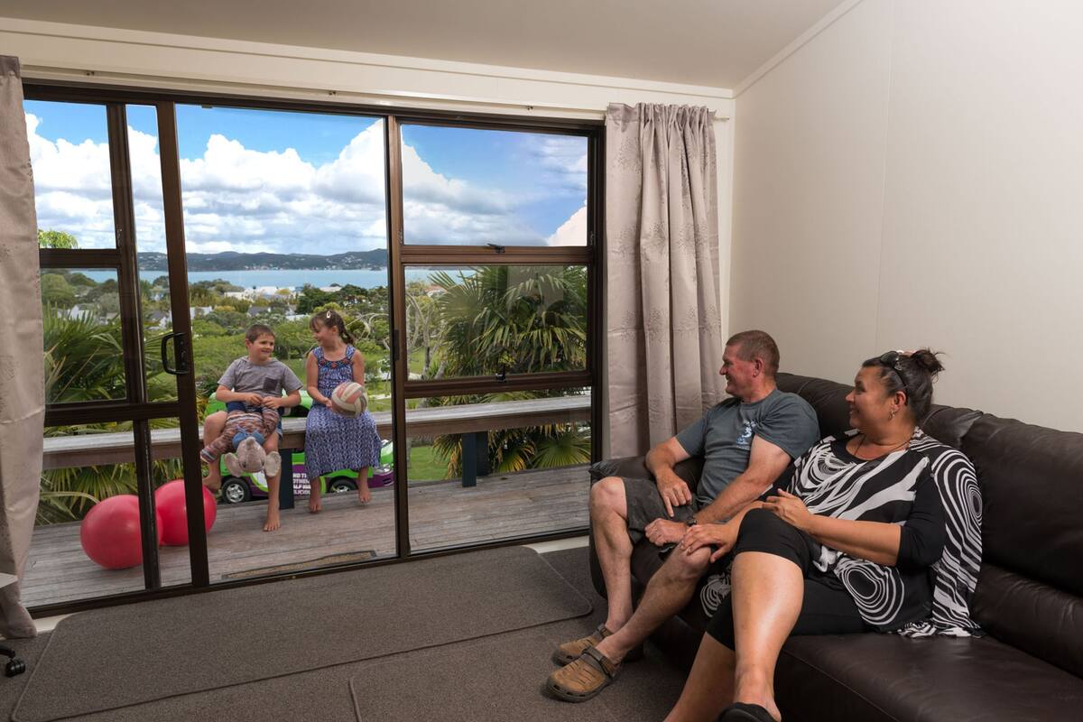 A living room with a large sliding glass door leading to a balcony with a view of a lake and greenery.