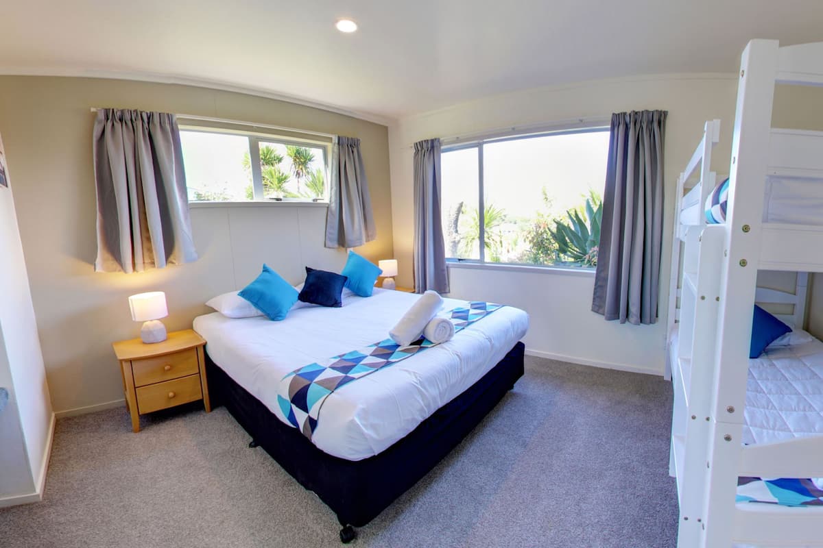 A bedroom with a bed, a nightstand, a window, and a bunk bed.