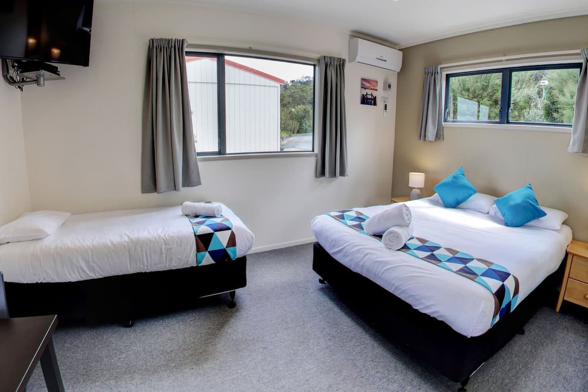A hotel room with two beds, a TV, and a window with curtains.