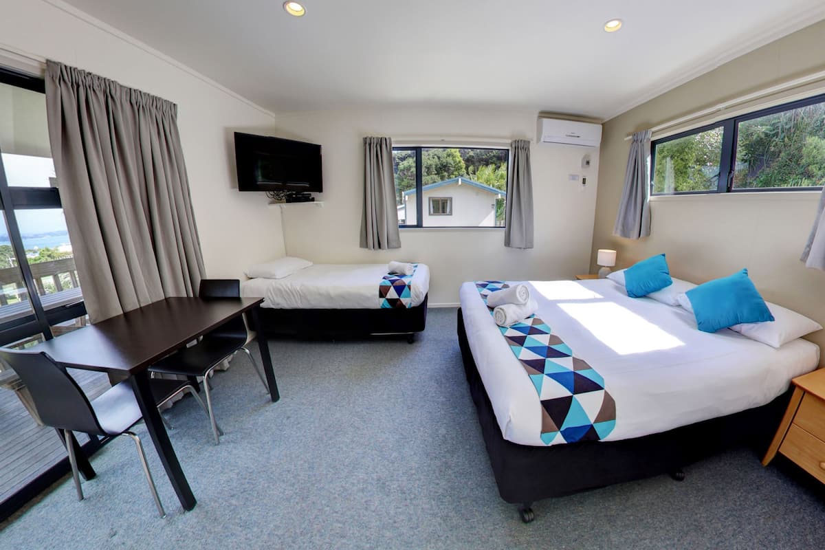 A hotel room with two beds, a desk, and a TV.