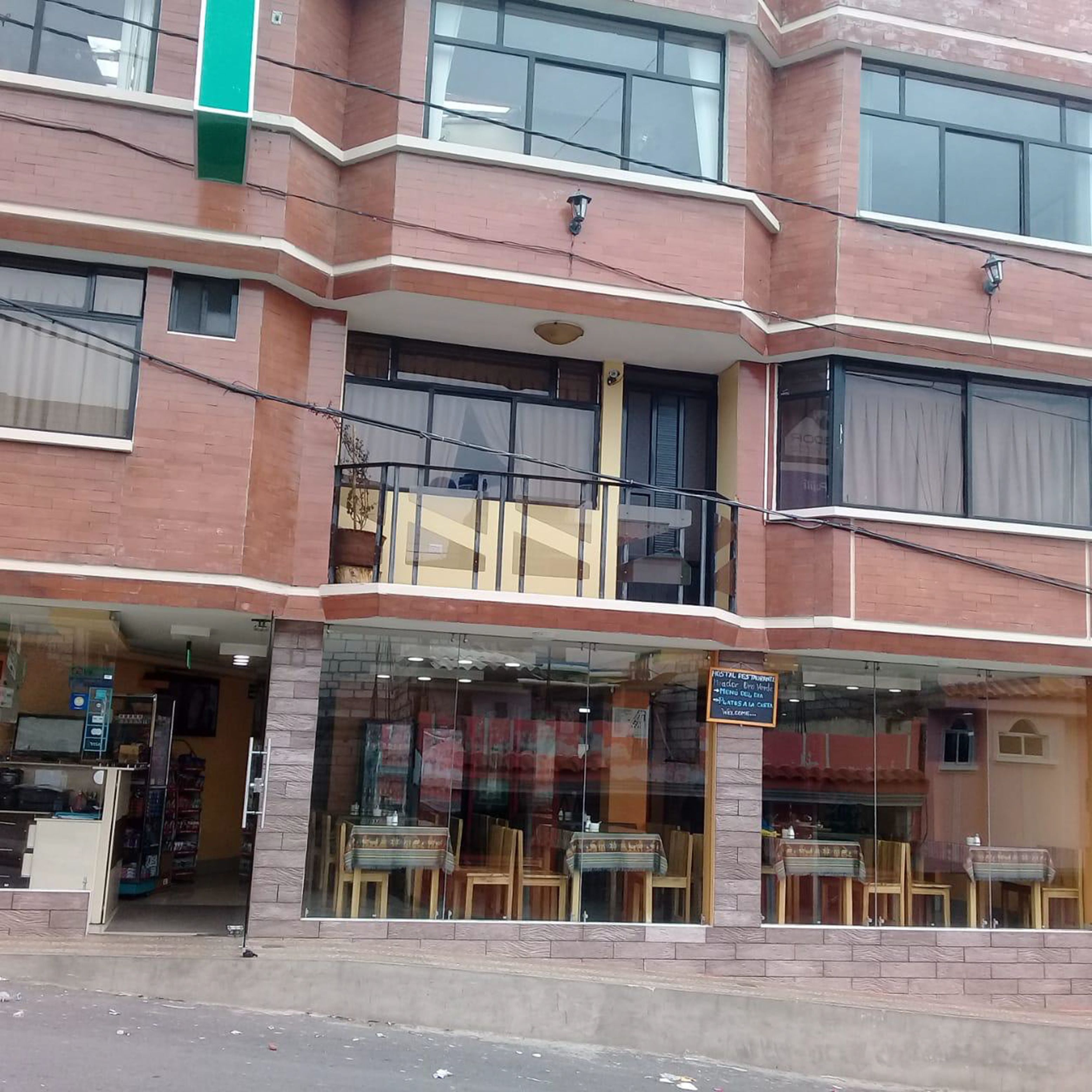 Un edificio de dos pisos con un restaurante en la planta baja que ofrece mesas al aire libre.
