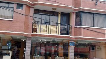 Un edificio de dos pisos con un restaurante en la planta baja que ofrece mesas al aire libre.