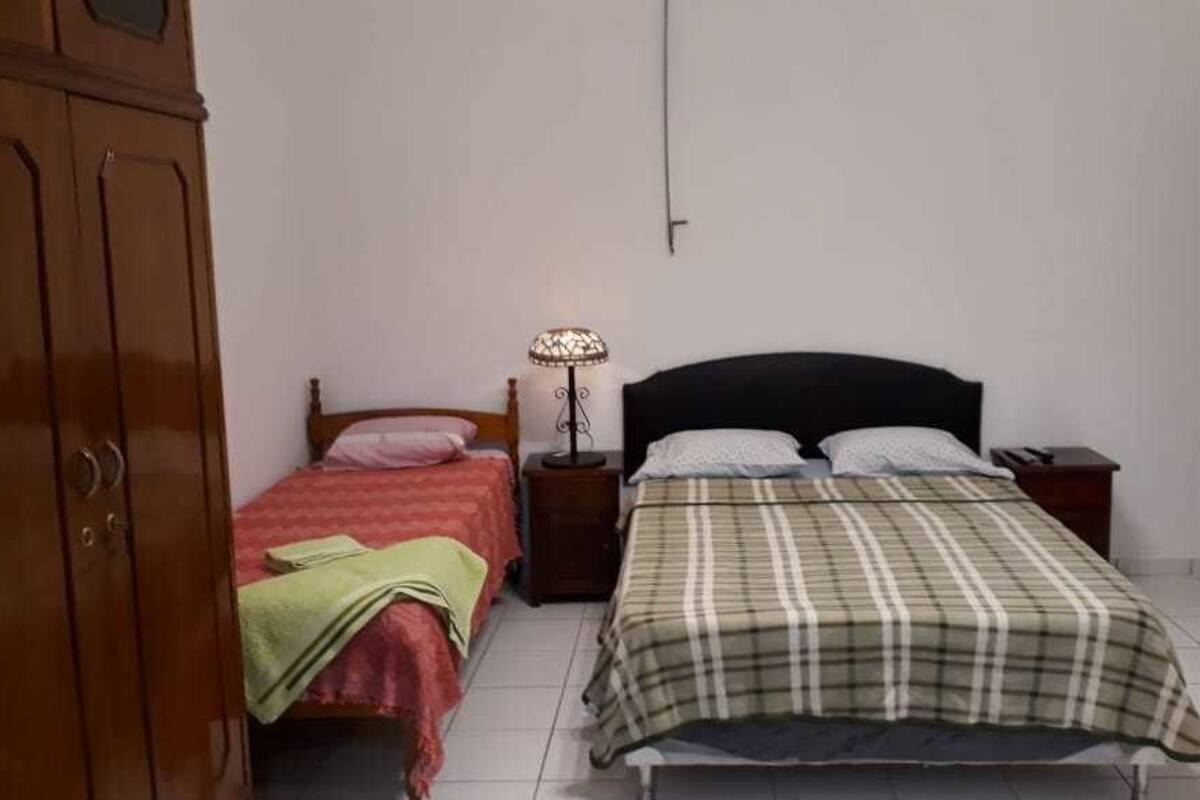A bedroom with two beds, a wardrobe, a bedside lamp, and a door.