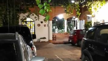 Un área de estacionamiento con coches aparcados bajo un árbol.