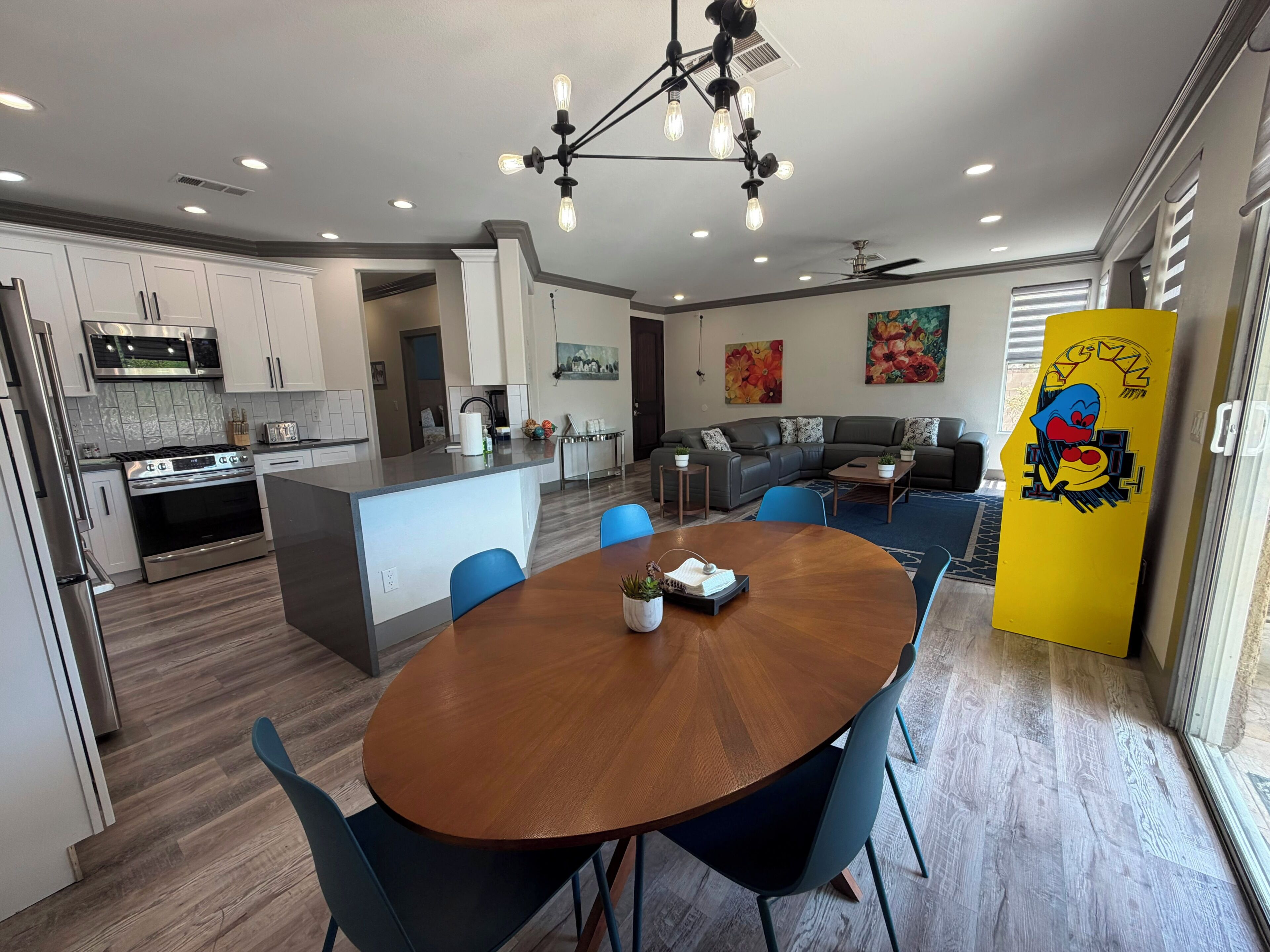 Une cuisine moderne avec un îlot central, un coin repas doté d’une table ronde et un salon avec un canapé d’angle.