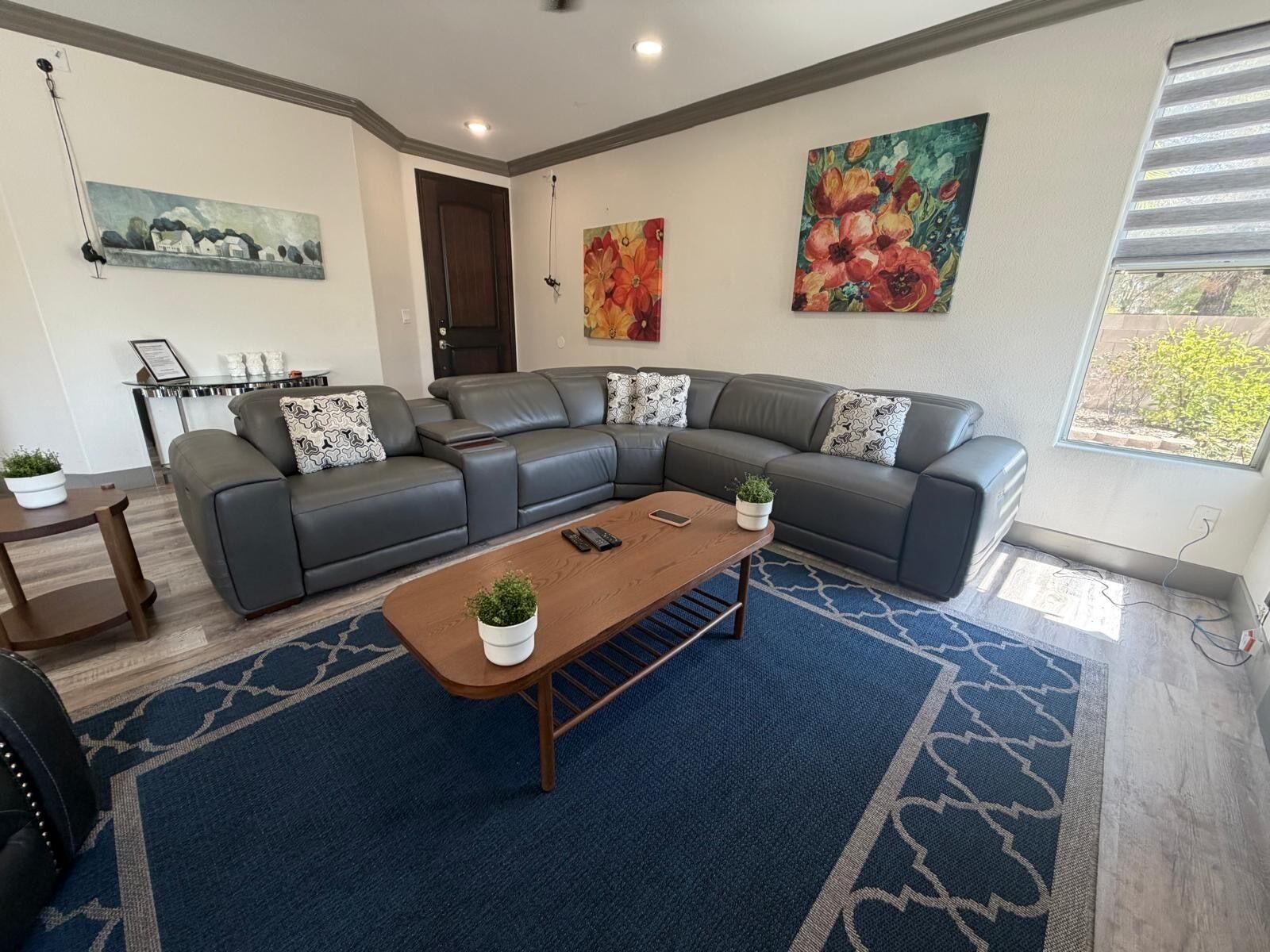 Un salon moderne avec un canapé d’angle, une table basse et un tapis à motifs bleus.