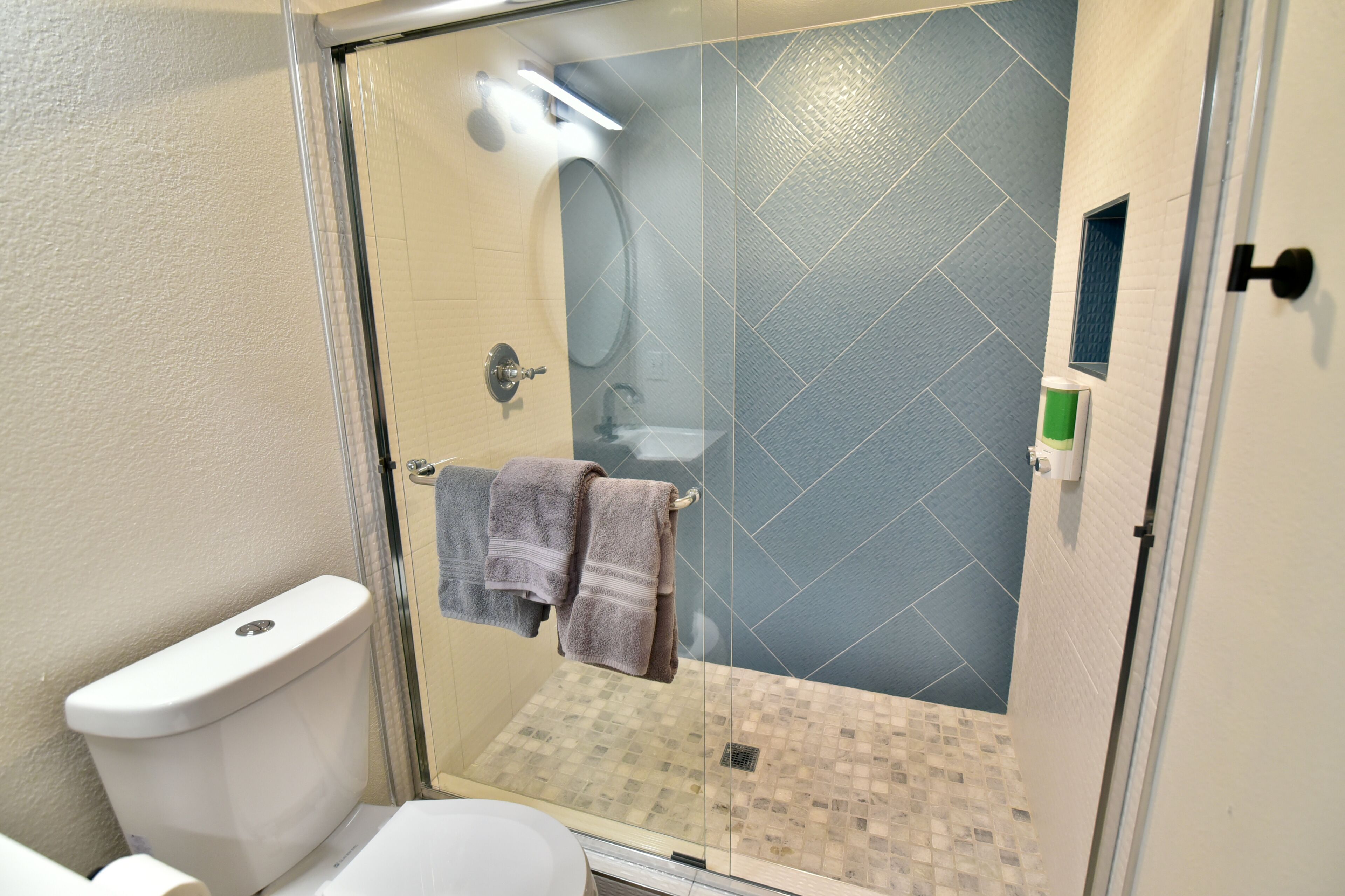 Une salle de bain avec une douche à parois de verre, des toilettes et un lavabo.