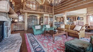 A spacious living area with a high ceiling, wooden beams, a fireplace, and a large rug. - Ten Mile Estate: Private Breckenridge Home with Hot Tub and Views (Breckenridge)