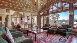A spacious living room with wooden beams, large windows, and a view of the outdoors. - Ten Mile Estate: Private Breckenridge Home with Hot Tub and Views (Breckenridge)