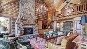 A log cabin interior with a stone fireplace, wooden furniture, and a balcony. - Ten Mile Estate: Private Breckenridge Home with Hot Tub and Views (Breckenridge)