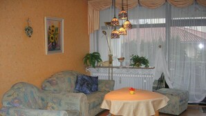 A cozy living room with patterned sofas, a small table with a bowl, and hanging lamps. - Haus Hamburg (Bad Fuessing)