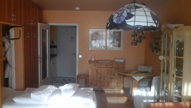 A bedroom with a bed, a wardrobe, a cabinet, a small table, and a hanging lamp. - Haus Hamburg (Bad Fuessing)