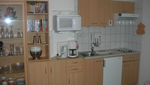 A kitchen with wooden cabinets, a microwave, a coffee maker, and a dishwasher. - Haus Hamburg (Bad Fuessing)