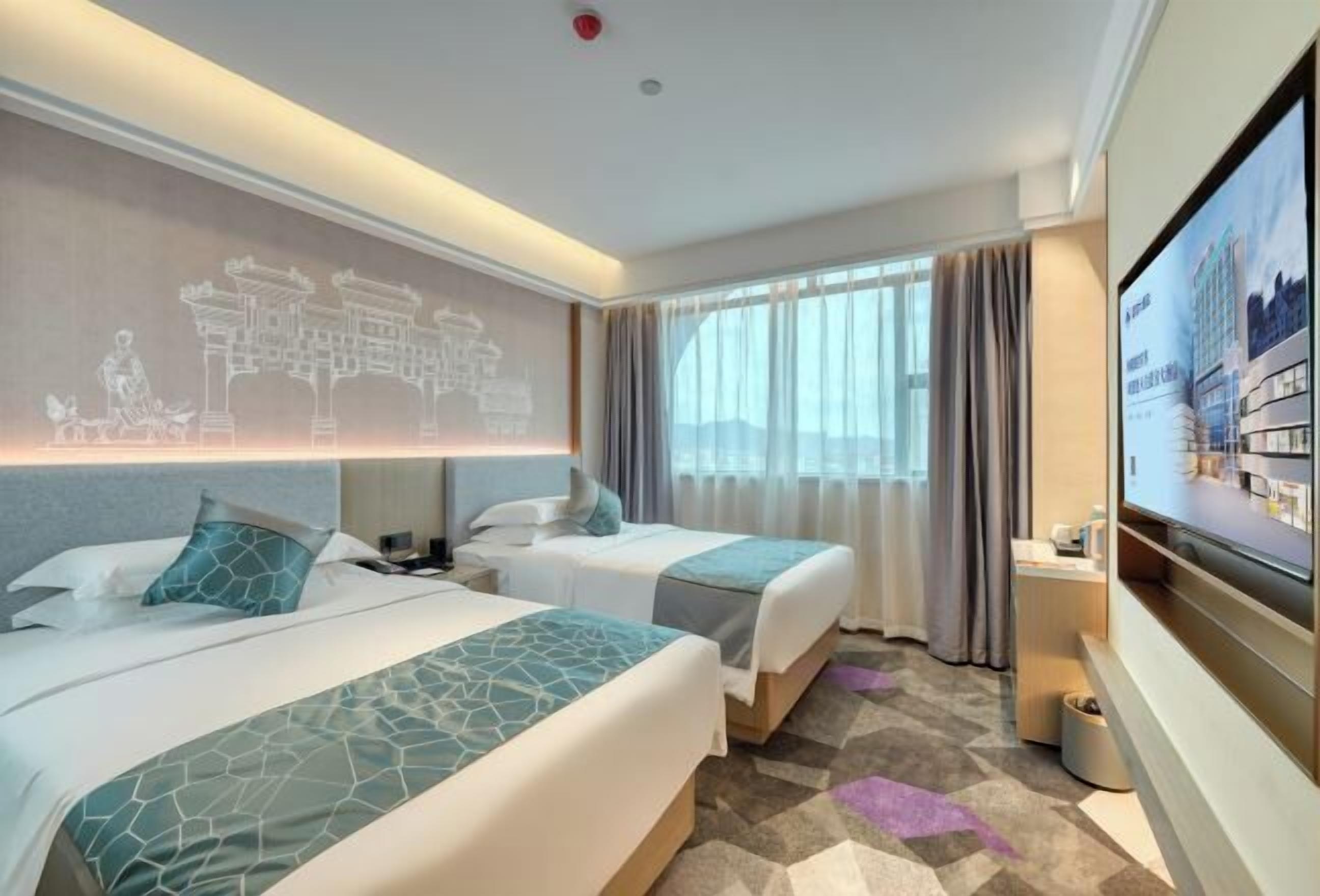 Habitación de hotel con dos camas, televisión, escritorio y un amplio ventanal con cortinas.