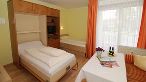 A bedroom with a bed, a desk with a chair, a wardrobe, and a window with curtains. - Haus Salzburg (Bad Fuessing)