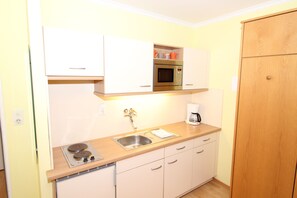 A compact kitchen with a microwave, coffee maker, and a sink.