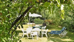 A patio with a table and chairs, a blue lounge chair, and a white umbrella. - Haus Salzburg (Bad Fuessing)