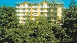 A multi-story hotel with balconies, surrounded by dense foliage. - Haus Salzburg (Bad Fuessing)
