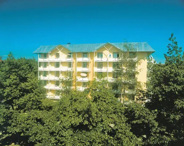 A multi-story hotel with balconies, surrounded by dense foliage.
