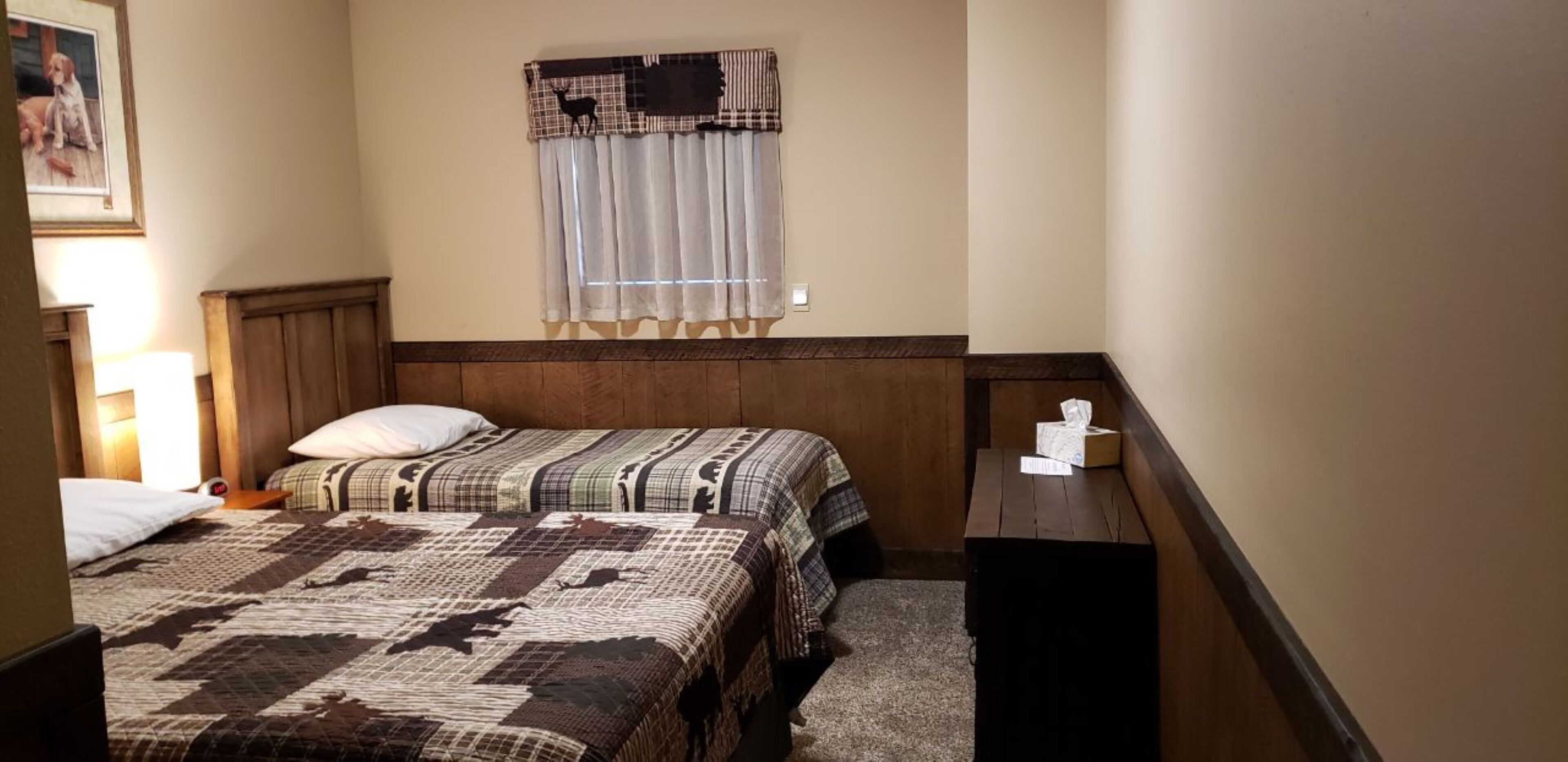 Ein kleines, gemütliches Schlafzimmer mit einem Bett, einem Nachttisch, einem Fenster mit Vorhang und einem gerahmten Bild an der Wand.