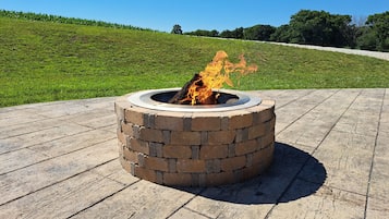 A circular fire pit with a brick exterior, surrounded by a wooden deck.