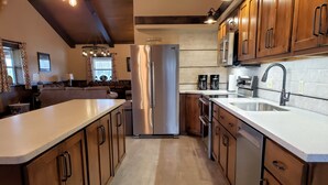 A modern kitchen with wooden cabinets, stainless steel appliances, and a large island. - Lost Branch Lodge. Complete exterior remodel, spring 2026! (Brashear)