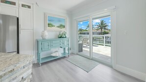 A kitchen with a stone countertop, a white refrigerator, a teal cabinet, and a painting of a beach scene. -  Beautiful Waterfront Pool Home, Walk to Beach, Pool/PPong Tbl (Marco Island)