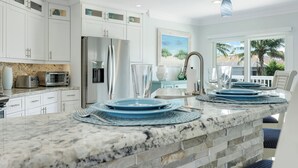 A modern kitchen with white cabinets, a granite countertop, and a view of the outdoors. -  Beautiful Waterfront Pool Home, Walk to Beach, Pool/PPong Tbl (Marco Island)