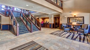 A spacious lobby with a grand staircase, a reception desk, and comfortable seating areas. - ON THE SLOPES. FAST RESPONSE. Ski Side Corner Unit, Crystal Peak Lodge 2BR/2BA (Breckenridge)