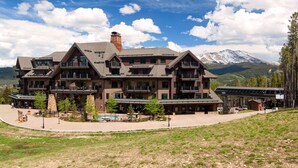 A large, multi-story lodge with a prominent chimney, balconies, and a pool area. - ON THE SLOPES. FAST RESPONSE. Ski Side Corner Unit, Crystal Peak Lodge 2BR/2BA (Breckenridge)