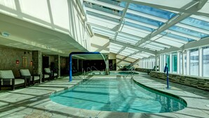 An indoor swimming pool with a glass ceiling, stone flooring, and lounge chairs. - ON THE SLOPES. FAST RESPONSE. Ski Side Corner Unit, Crystal Peak Lodge 2BR/2BA (Breckenridge)