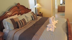 A neatly made bed with a striped blanket and pillows, a bedside lamp, and a wooden headboard. - Four Corners Area Pool Homes by ORB (Davenport)