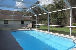 A covered swimming pool with a chair and a house in the background. - Four Corners Area Pool Homes by ORB (Davenport)