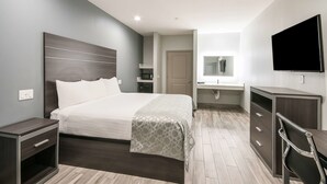A modern hotel room with a large bed, a desk, a chair, a TV, and a wardrobe. - Americas Best Value Inn & Suites NE Houston Downtown I-610 (Houston)
