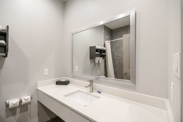 A modern bathroom with a white sink, a large mirror, and a towel rack. - Americas Best Value Inn & Suites NE Houston Downtown I-610 (Houston)