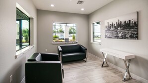 A modern room with a sofa, a white console table, and a cityscape painting on the wall. - Americas Best Value Inn & Suites NE Houston Downtown I-610 (Houston)