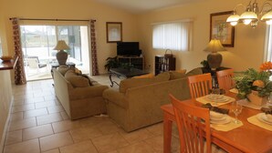 Una sala de estar con sofá, una mesa de comedor para dos personas y televisor.