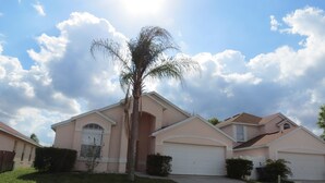 Una casa de un solo piso con garaje, un pequeño jardín delantero y una palmera.