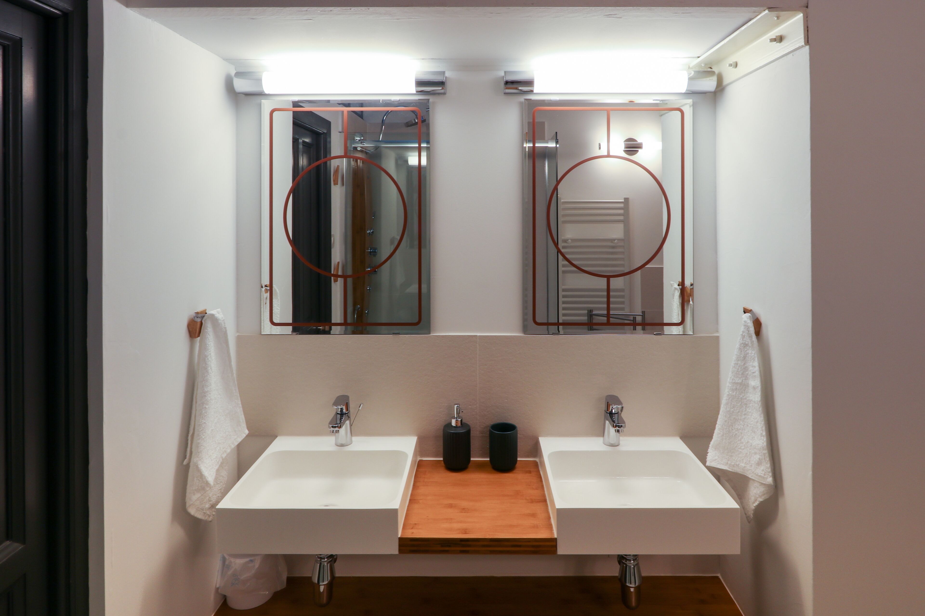 A bathroom with two sinks, a mirror, and a wooden shelf.