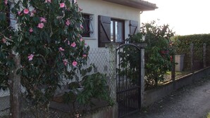 A house with a white exterior, dark shutters, and a metal gate.