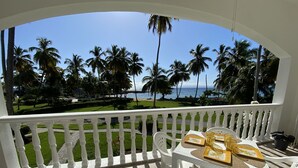 Un balcon avec vue sur l’océan et les palmiers.