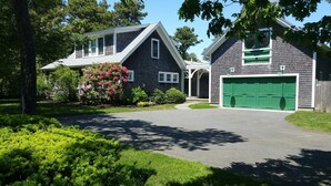 Ein zweistöckiges Haus mit Garage, umgeben von Grünflächen und Bäumen.