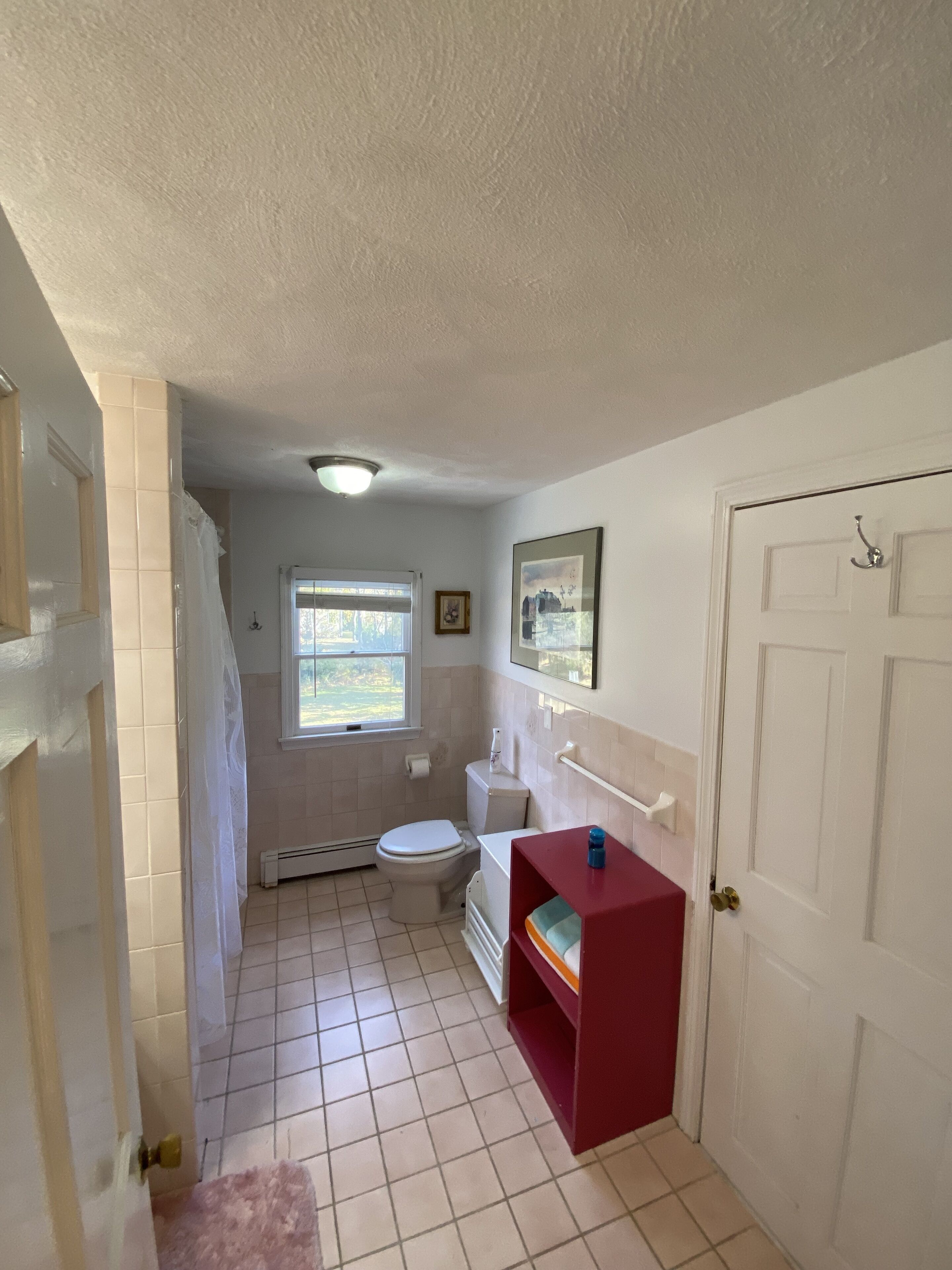A small, clean bathroom with a toilet, sink, and shower area.