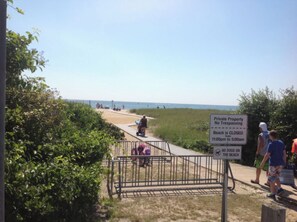 Een strandpad met een bord waarop staat dat het strand gesloten is van 23:00 tot 05:00 uur en dat honden niet toegestaan zijn.