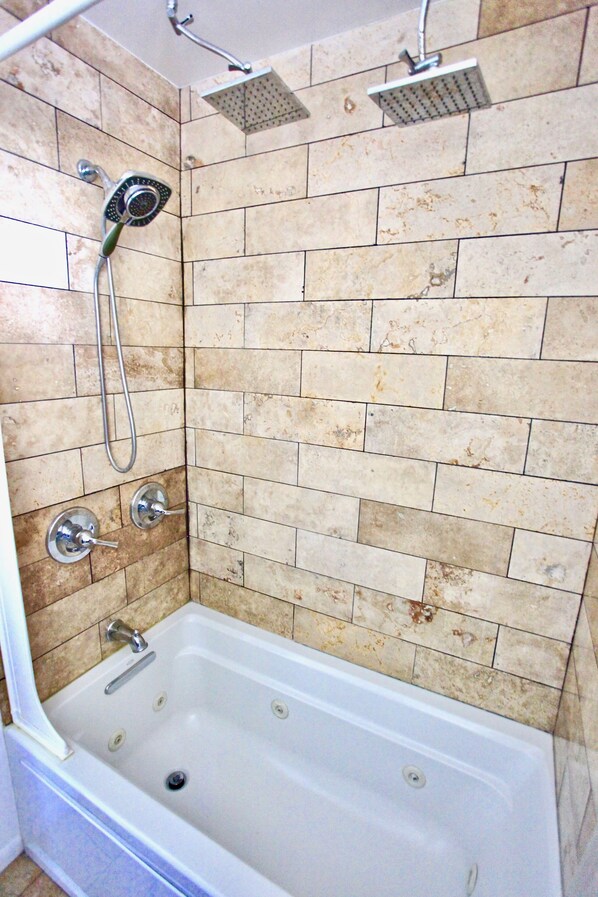 A bathroom with a bathtub, a showerhead, and a handheld showerhead.